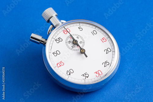 Analogue metal stopwatch on the blue background.