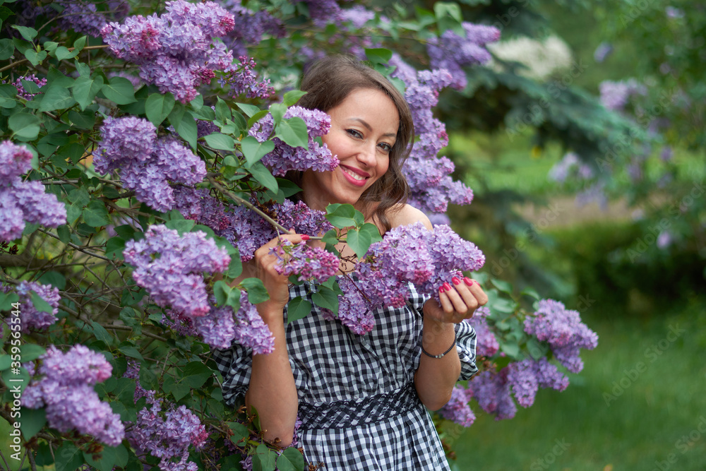 beautiful curly haired girl with a smile on her face in blooming lilac beautiful curly haired girl with a smile on her face in blooming lilac