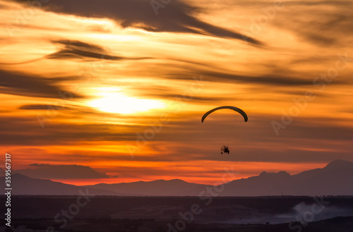 paragliding at sunset with the sun and clouds