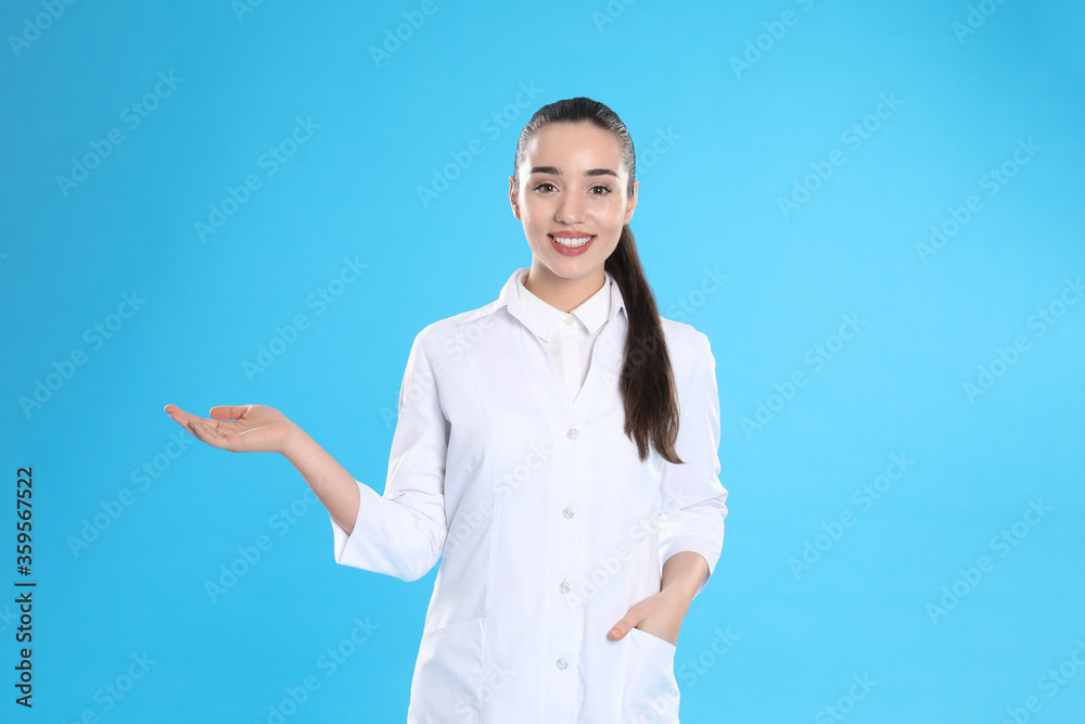 Happy young woman in lab coat on light blue background Happy young woman in lab coat on light blue background