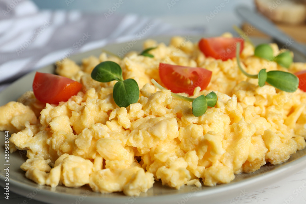 Tasty scrambled eggs with sprouts and cherry tomato on grey plate, closeup
