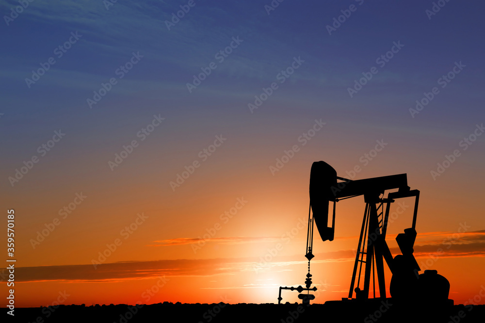 Silhouette of crude oil pump at sunset. Space for text