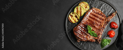 Slate plate with grilled meat steak and space for text on black table, top view. Banner design