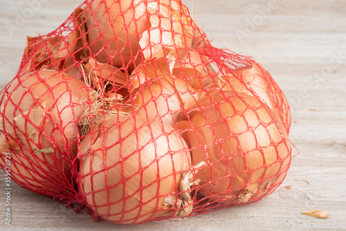 White Onions In A Flexible Red Wire Mesh Retail Packaging Bag