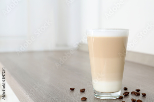 Delicious latte macchiato and coffee beans on wooden table indoors. Space for text photo