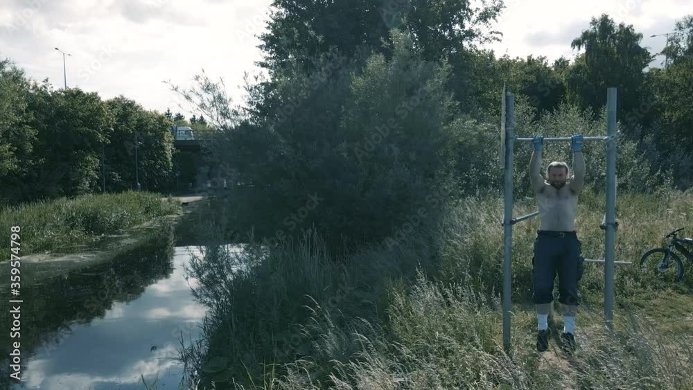 Man Doing Pull Ups On The M50 Sign Next To Grand Canal In Dublin, Ireland On A Sunny Day- Medium Panning Shot