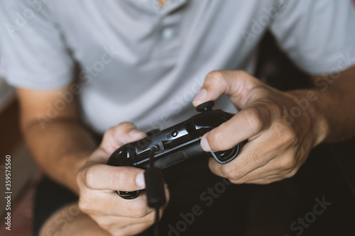closeup hand man holding black joystick. paly game. soft-focus and over light in the background