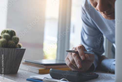 Businessman using calculator to calculate business report working in office