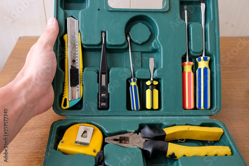 Man hand opens old square green tool box with manual set tools for home repair. Top view