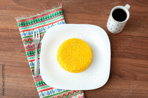 tasteful and colorful brazilian corn couscous served with a cup of coffee on a wooden table photo