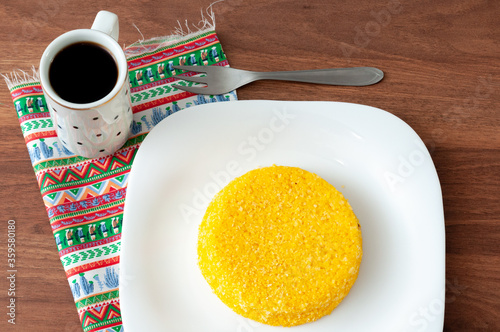 tasteful and colorful brazilian corn couscous served with a cup of coffee on a wooden table photo