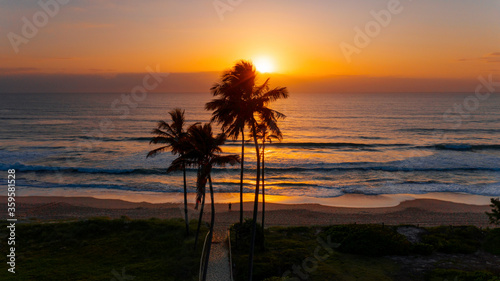 Silhouette of a person standing on the beach with an ocean sunrise and palm tree s  Main beach Gold Coast.