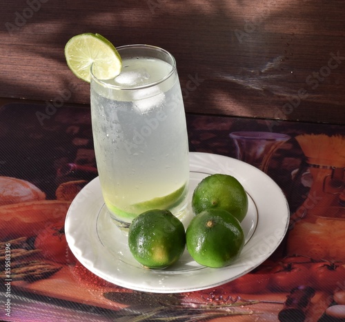 
Toma panorámica de un vaso de refrescante limonada con hielo y una rodaja de limón en el borde del vaso.