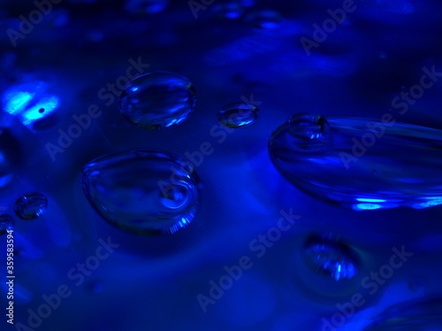 blurred blue water drops with shiny on glass , abstract background, dark and sweet color ,macro bubble for card design 