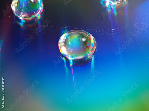 blurred water droplets with blue light on bright backgronud, dark and shiny , abstract background, macro image for card design © Suganya