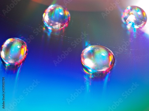 blurred water droplets with blue light on bright backgronud, dark and shiny , abstract background, macro image for card design © Suganya
