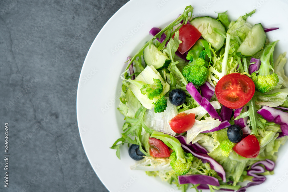 A plate of delicious and healthy green vegetable salad. A plate of delicious and healthy vegetable salad on a gray concrete floor.
