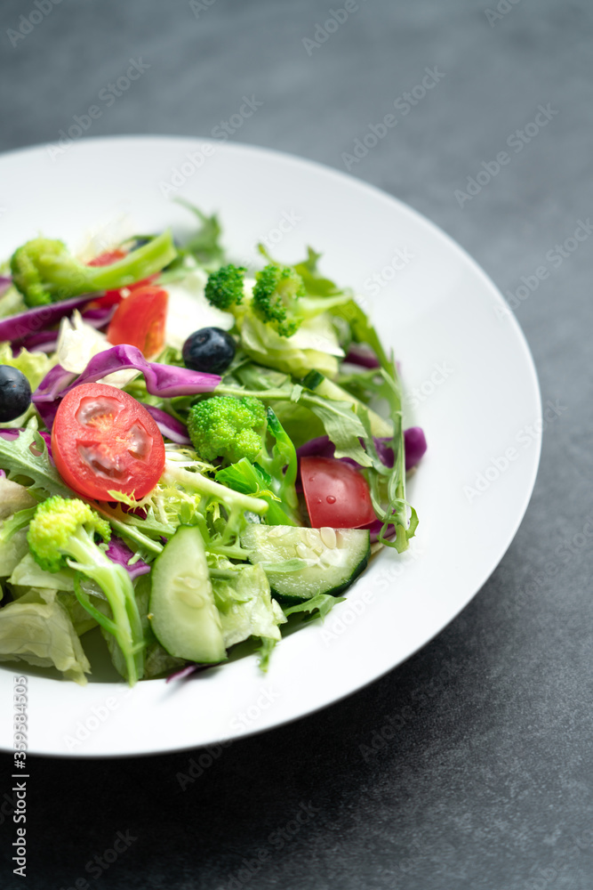 A plate of delicious and healthy green vegetable salad. A plate of delicious and healthy vegetable salad on a gray concrete floor.
