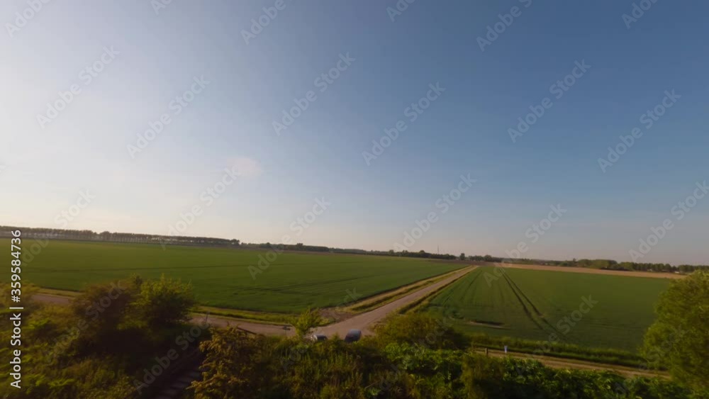 Aerial drone flight through forest trees revealing green Kortgene farm field Aerial drone flight through forest trees revealing green Kortgene farm field