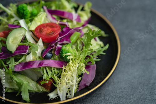 Close-up of a plate of delicious healthy green vegetable salad. A plate of delicious and healthy vegetable salad on a gray concrete floor.