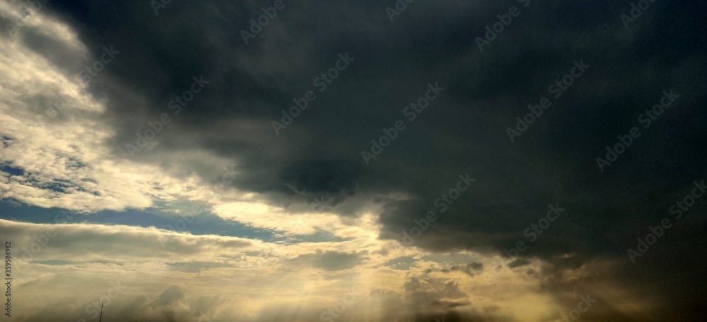 Gazipur, Bangladesh-June 21, 2020: Beautiful evening Skyscape after rain. Sun's rays shine through the hole in black clouds over the factory buildings. Sky, Golden sky. Natural background. Gazipur, Bangladesh-June 21, 2020: Beautiful evening Skyscape after rain. Sun's rays shine through the hole in black clouds over the factory buildings. Sky, Golden sky. Natural background.