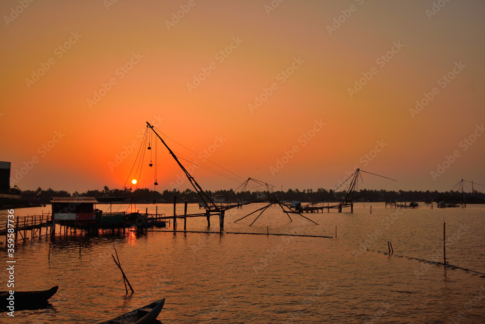 Silhouette of chinese fishing nets in kochi backwaters during sunset.