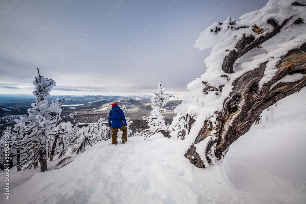 Man looking off into the mountains on a snowy stormy day