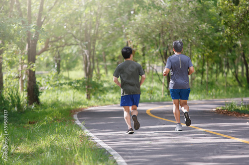 Father and adult son jogging on the park path © toa555