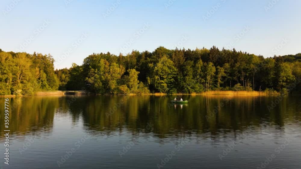 Aerial view of a boat with two tourists enjoying the lake at golden hour Aerial view of a boat with two tourists enjoying the lake at golden hour
