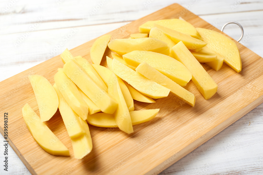 Sliced potato on a cutting board on a light wooden background. Preparing potatoes for cooking.