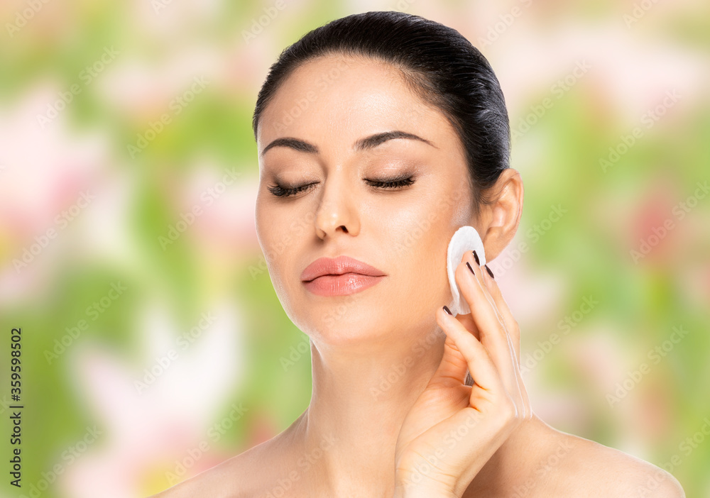 Beautiful brunette woman with cotton pad over blurred background. Health and beauty concept
