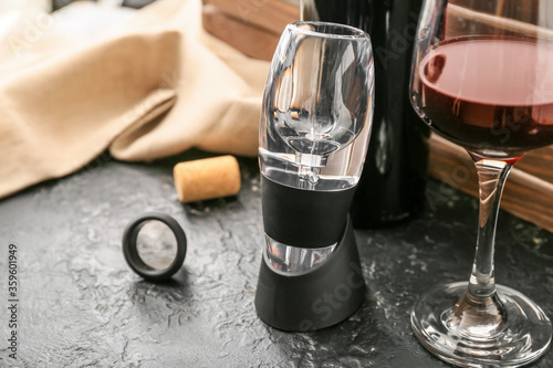 Aerator and glass of wine on dark background