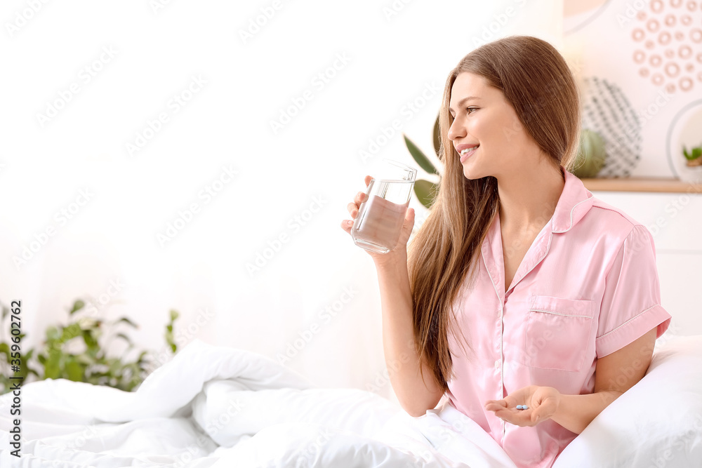 Young woman taking sleeping pills in bedroom Young woman taking sleeping pills in bedroom