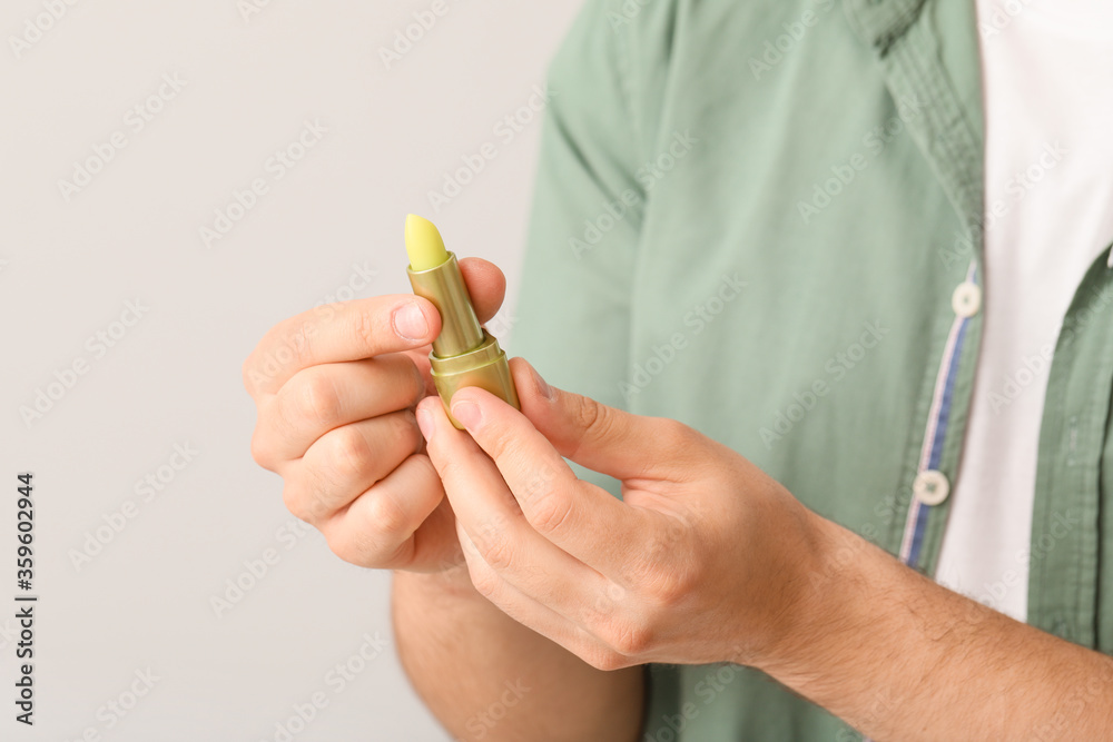 Handsome young man with lip balm on light background, closeup Handsome young man with lip balm on light background, closeup