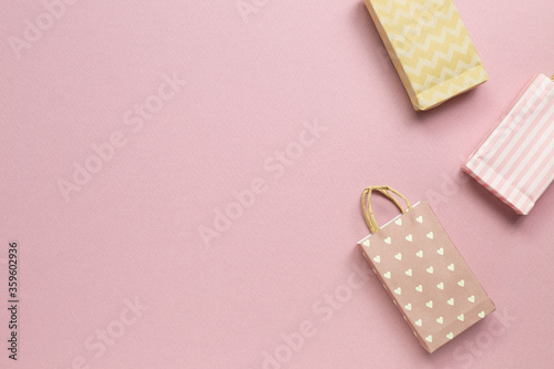 Colorful paper shopping bags on pink background. top view