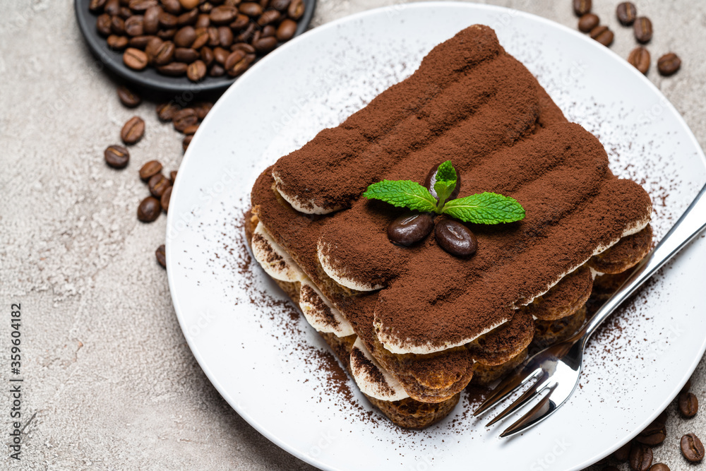 Classic tiramisu dessert on ceramic plate on concrete background