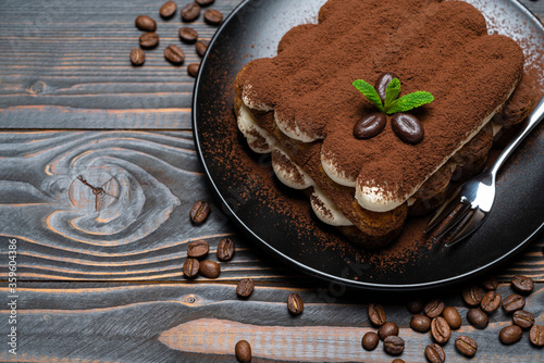 Classic tiramisu dessert on ceramic plate on wooden background