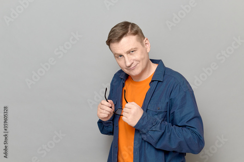 Portrait of friendly mature man holding glasses in hands and smiling