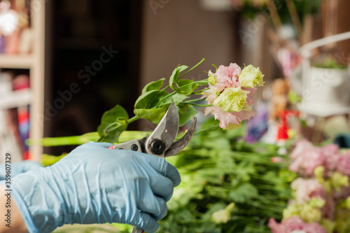 The florist works with flowers. Make a Bouquet of eustoma. Florist at work. Florist's workplace. The florist works in gloves. Small business in a pandemic.