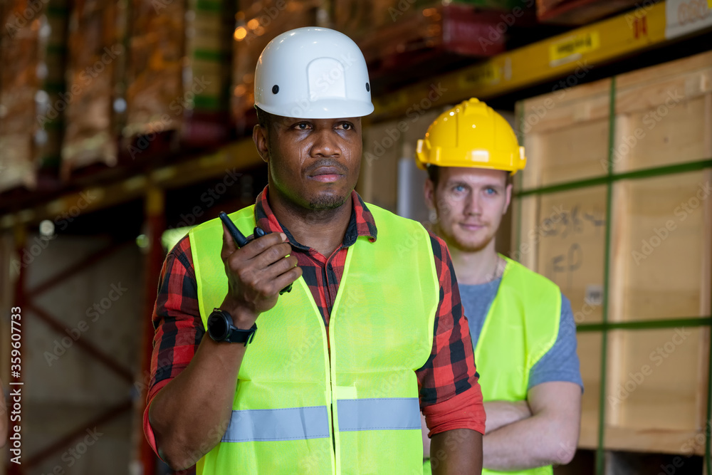 Warehouse worker using handheld radio receiver for communication in a large warehouse.