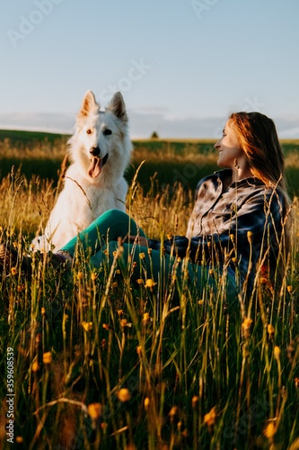 woman with dog at sunset in a meadow 