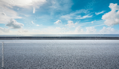 Asphalt road and lake water under blue sky. © ABCDstock