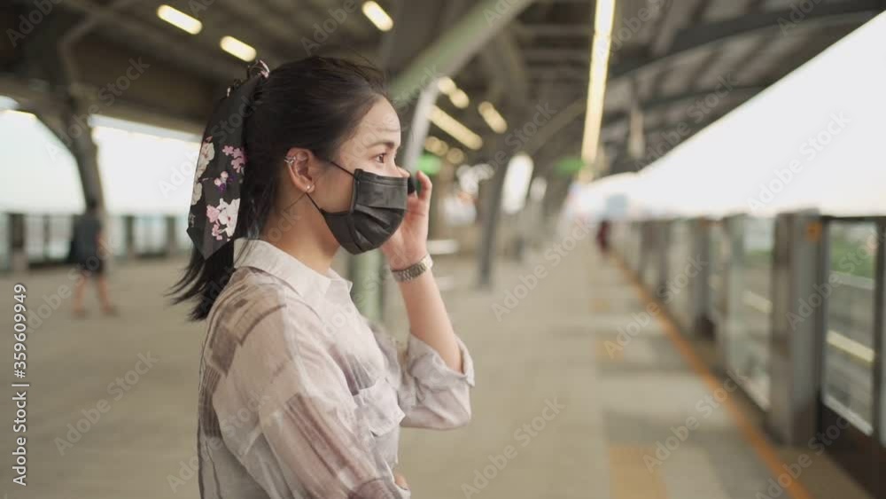 Asian female commuter wear black mask standing on sky train platform