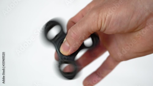 Popular Fidget Spinner toy rotating between fingers of white man. photo