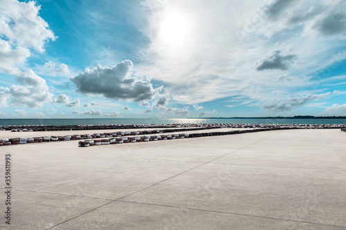 Wide cement road and lake under blue sky.