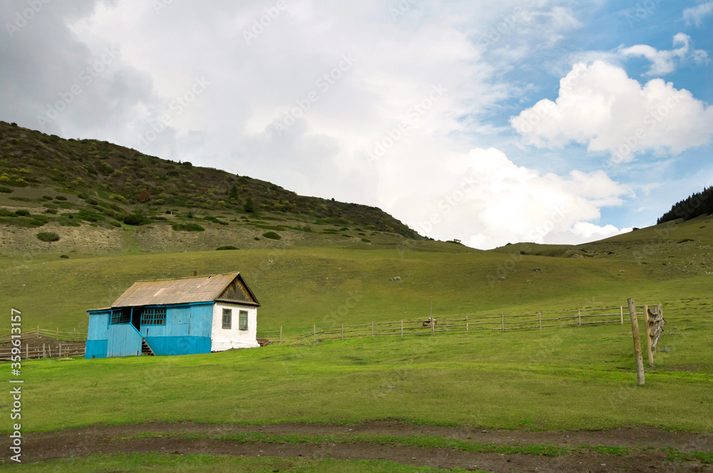 Abandoned introvert house with amazing green lawn at the foreground in Kyrgyzstan