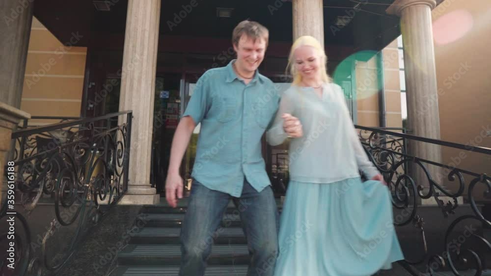 The guy with the girl down the stairs. They unusually synchronously rearrange their feet, holding each other's hands. In the background is the entrance to the hotel and large columns. The guy with the girl down the stairs. They unusually synchronously rearrange their feet, holding each other's hands. In the background is the entrance to the hotel and large columns.