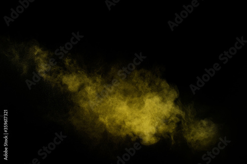 Yellow powder explosion on black background. Colored powder cloud. Colorful dust explode. Paint Holi.