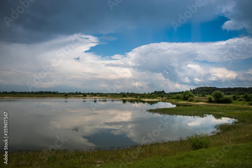 Thunderclouds over the lake. Reflection of the sky in the water.