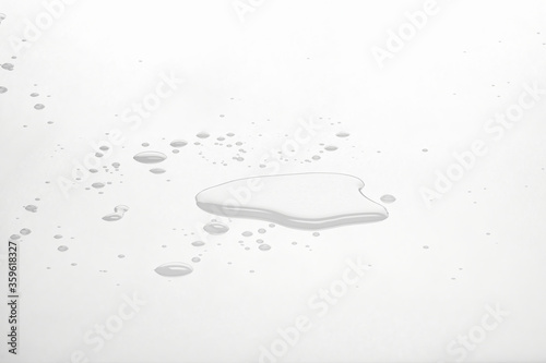 Water puddles and droplets on white reflective surface. Frontal view and deep focus. 